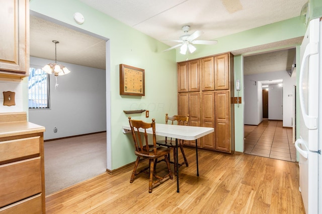 dining room featuring ceiling fan with notable chandelier, light hardwood / wood-style floors, and a textured ceiling