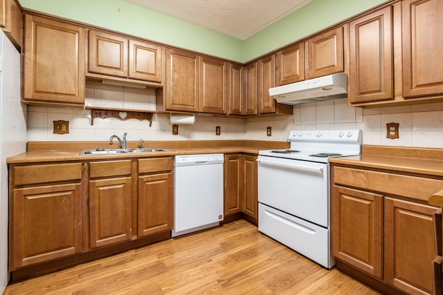 kitchen featuring tasteful backsplash, a textured ceiling, white appliances, sink, and light hardwood / wood-style flooring