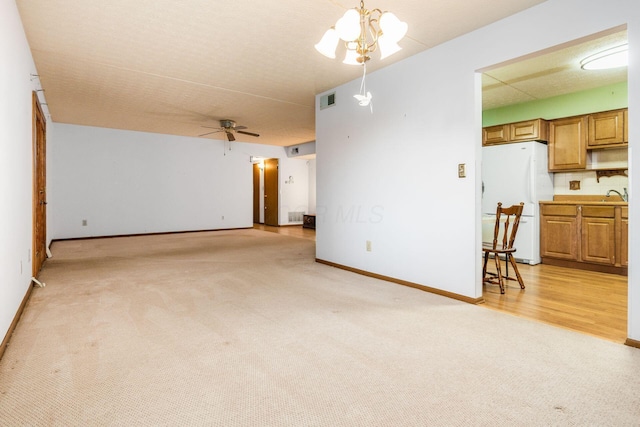 unfurnished living room with ceiling fan with notable chandelier, light colored carpet, and sink