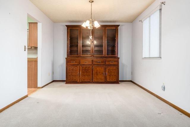 unfurnished dining area with light carpet and an inviting chandelier