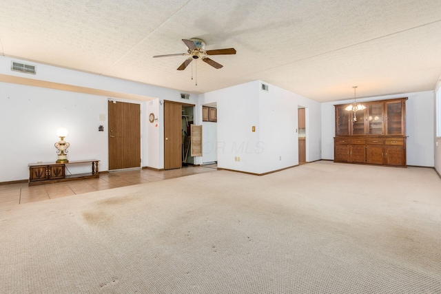 unfurnished living room featuring ceiling fan with notable chandelier, a textured ceiling, and carpet floors