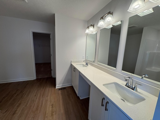 bathroom featuring wood-type flooring, vanity, and a textured ceiling