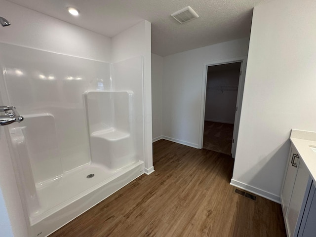 bathroom featuring a textured ceiling, vanity, hardwood / wood-style flooring, and walk in shower