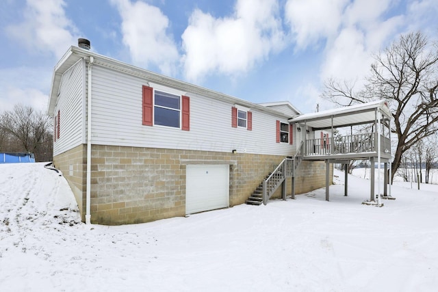 snow covered back of property featuring a garage