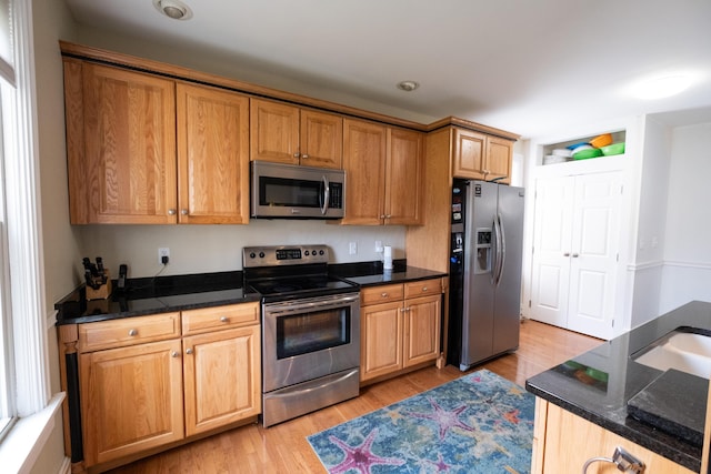 kitchen featuring dark stone countertops, light wood-type flooring, and stainless steel appliances