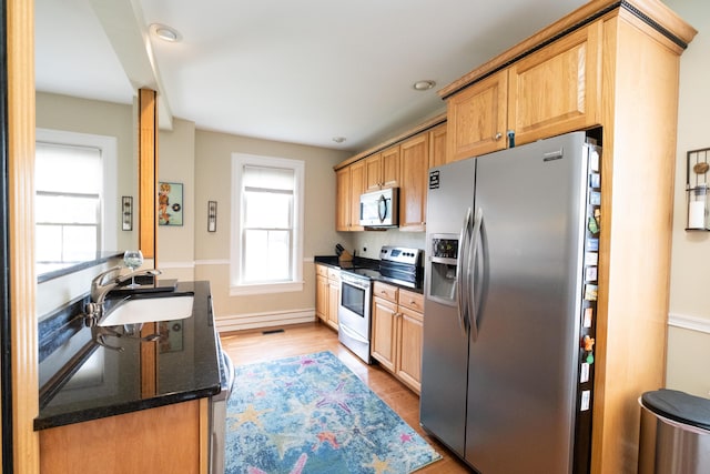 kitchen with a wealth of natural light, sink, stainless steel appliances, and light hardwood / wood-style floors