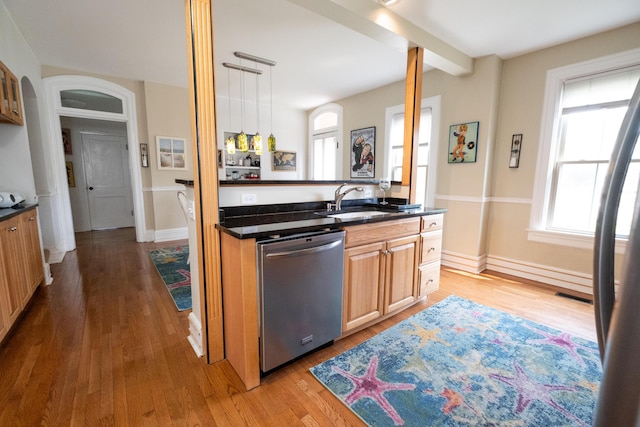 kitchen featuring light wood-type flooring, stainless steel dishwasher, sink, decorative light fixtures, and beamed ceiling