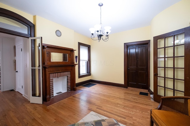 unfurnished living room with hardwood / wood-style flooring, a notable chandelier, and a fireplace