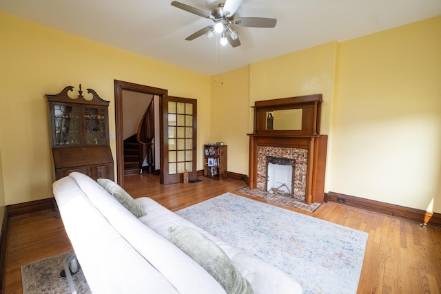 living room with hardwood / wood-style flooring, ceiling fan, and a high end fireplace