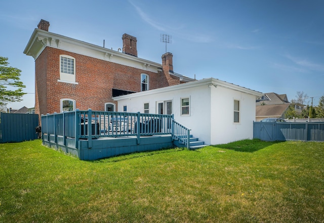 back of house featuring a lawn and a wooden deck