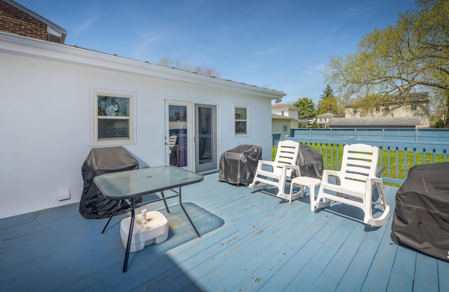 wooden deck featuring a lawn and a grill