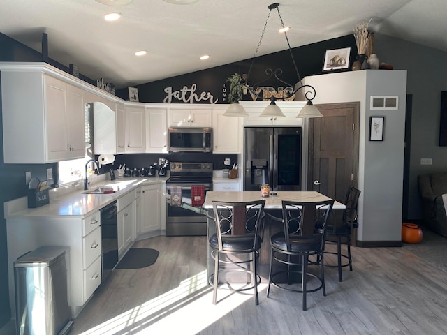 kitchen with white cabinetry, stainless steel appliances, pendant lighting, lofted ceiling, and a kitchen island