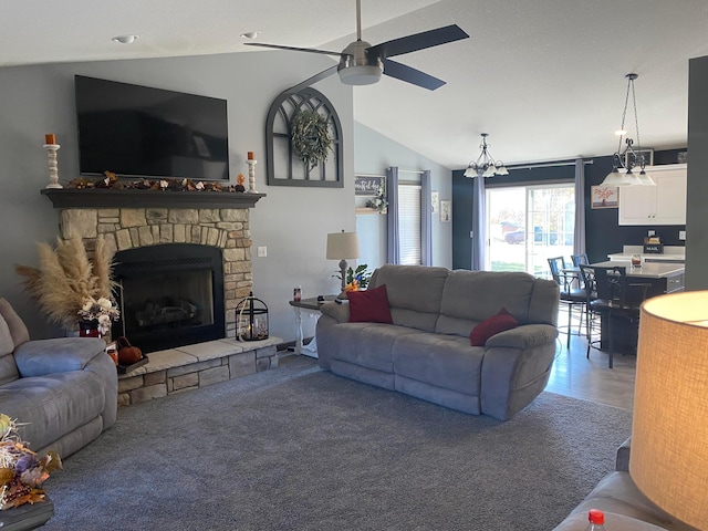 carpeted living room featuring ceiling fan with notable chandelier, a fireplace, and vaulted ceiling