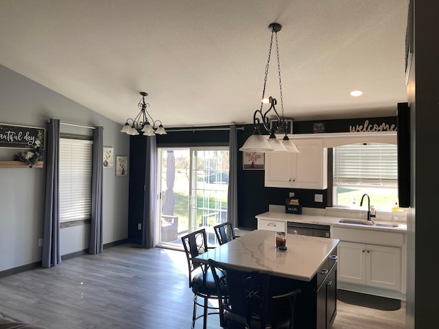 kitchen with white cabinetry, dishwasher, sink, decorative light fixtures, and a kitchen island