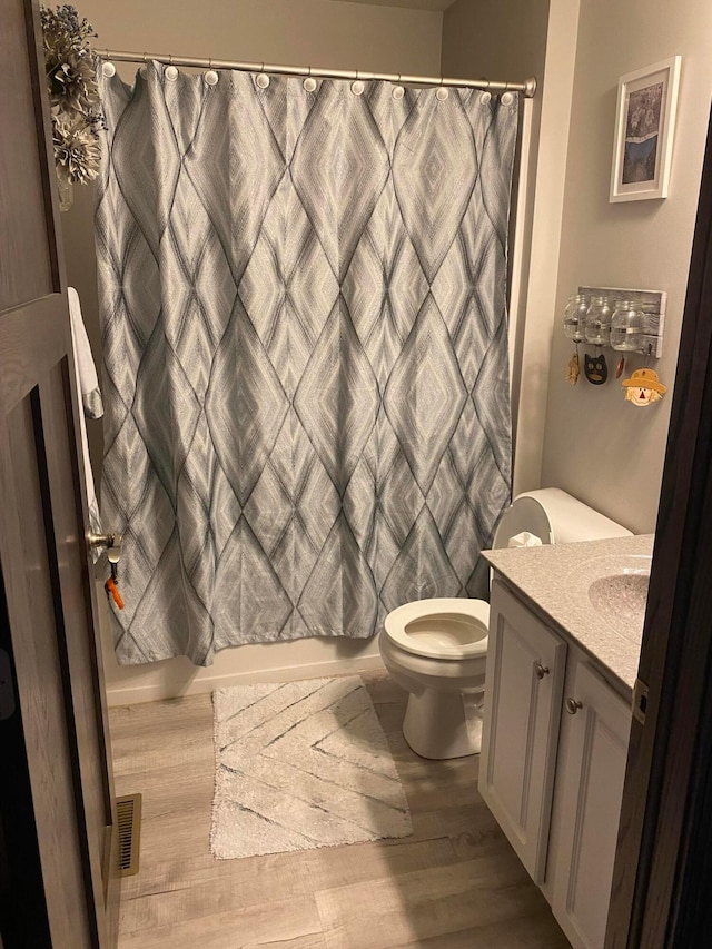 full bathroom featuring wood-type flooring, vanity, toilet, and shower / bath combination with curtain