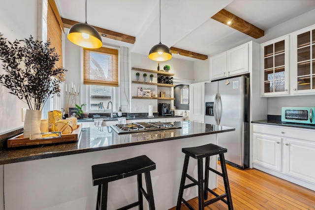 1030 Jaeger St, Columbus, OH 43206 - kitchen featuring appliances with stainless steel finishes, beamed ceiling, white cabinets, light wood finished floors, and glass insert cabinets