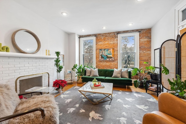 1030 Jaeger St, Columbus, OH 43206 - living room featuring plenty of natural light, a fireplace, wood finished floors, brick wall, and recessed lighting