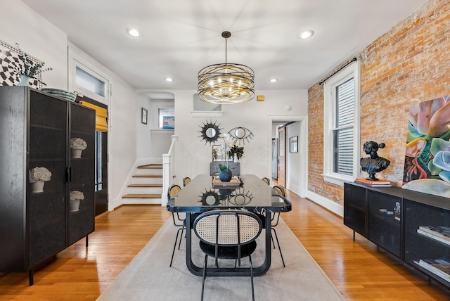1030 Jaeger St, Columbus, OH 43206 - dining space featuring brick wall, stairs, light wood-style flooring, a chandelier, and recessed lighting