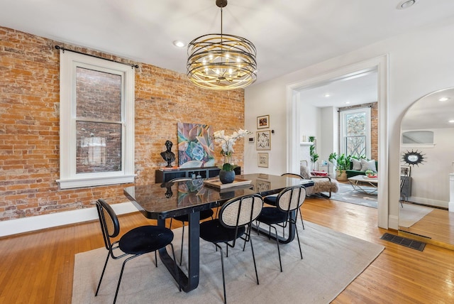 1030 Jaeger St, Columbus, OH 43206 - dining room with a chandelier, light wood-style flooring, brick wall, arched walkways, and recessed lighting