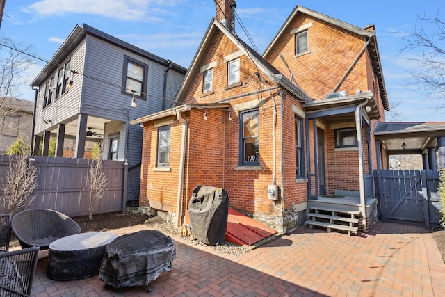 back of property with a patio area, a gate, fence, and brick siding