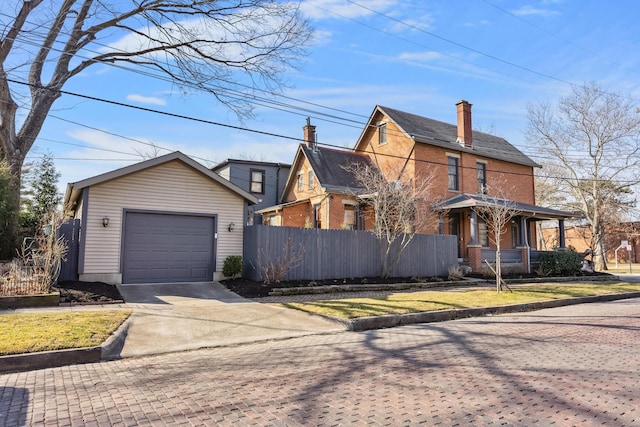 view of front of property featuring an outbuilding, driveway, fence, a garage, and brick siding