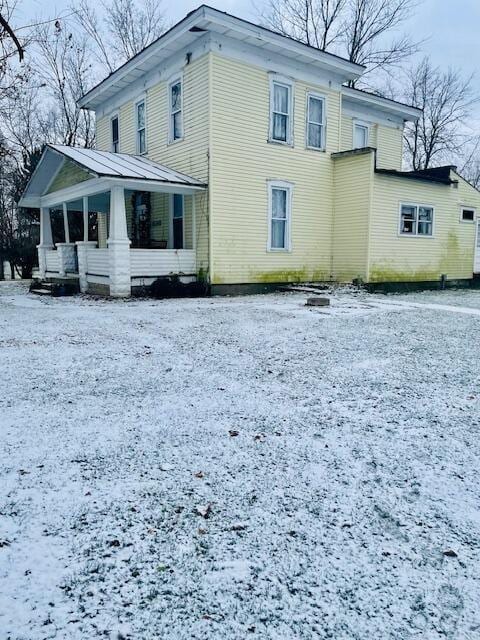 snow covered property featuring covered porch