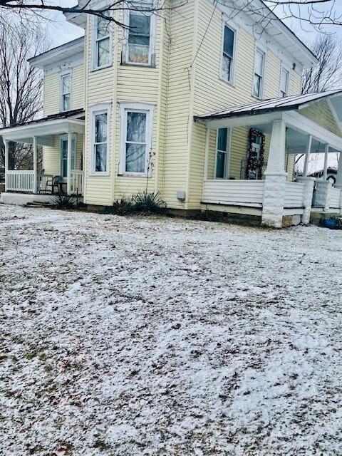 snow covered back of property with covered porch