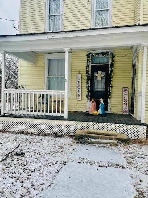 snow covered property entrance with a porch