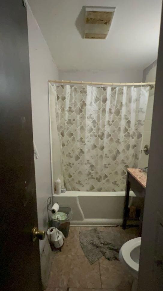 bathroom featuring shower / bath combination with curtain, toilet, and tile patterned floors