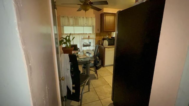 kitchen with ceiling fan, black fridge, and light tile patterned floors