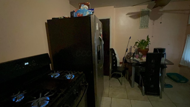 kitchen with stainless steel fridge, black gas range, and light tile patterned floors