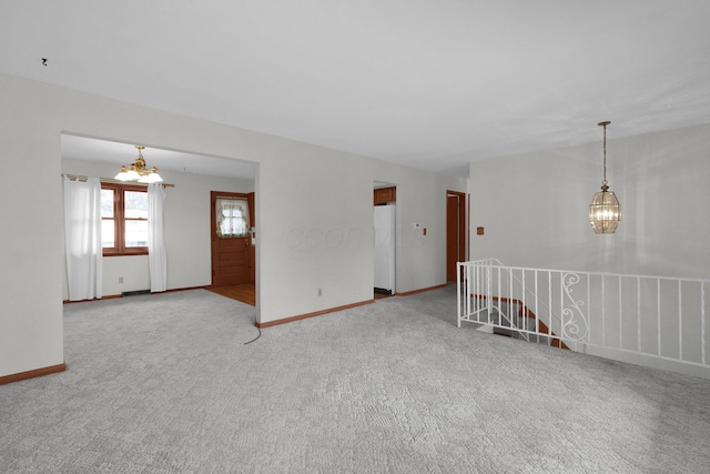 spare room featuring carpet flooring and a chandelier