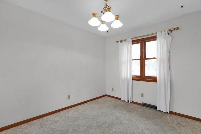 carpeted empty room featuring a chandelier