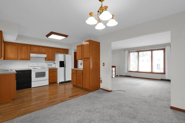 kitchen featuring white appliances, sink, a notable chandelier, dark hardwood / wood-style floors, and hanging light fixtures