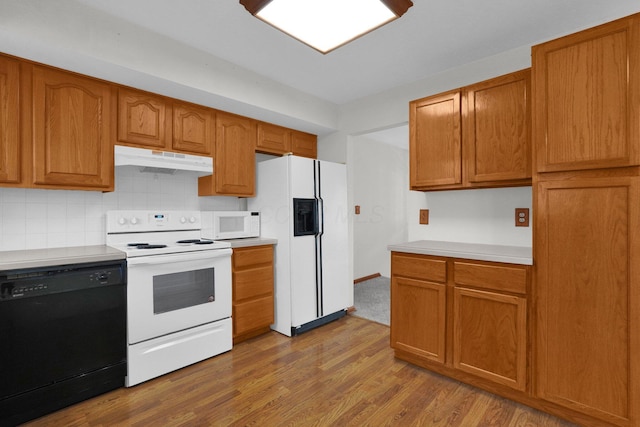 kitchen with decorative backsplash, light hardwood / wood-style floors, and white appliances