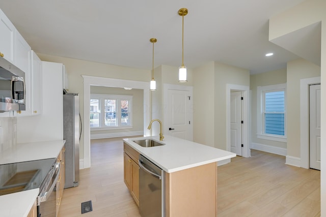 kitchen featuring stainless steel appliances, a kitchen island with sink, sink, light hardwood / wood-style floors, and white cabinetry