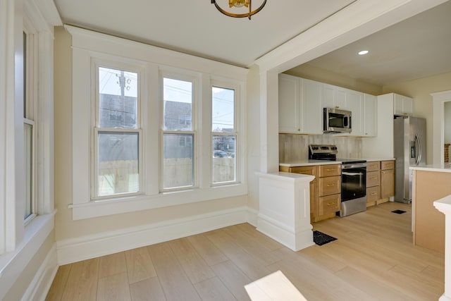 kitchen featuring backsplash, light wood-type flooring, white cabinetry, and stainless steel appliances