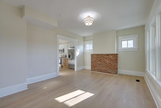 unfurnished living room featuring a wealth of natural light and light wood-type flooring