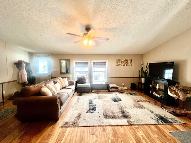 living room with hardwood / wood-style flooring, a textured ceiling, and ceiling fan