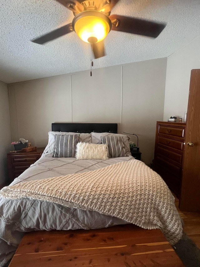 bedroom featuring dark wood-type flooring, a textured ceiling, and ceiling fan