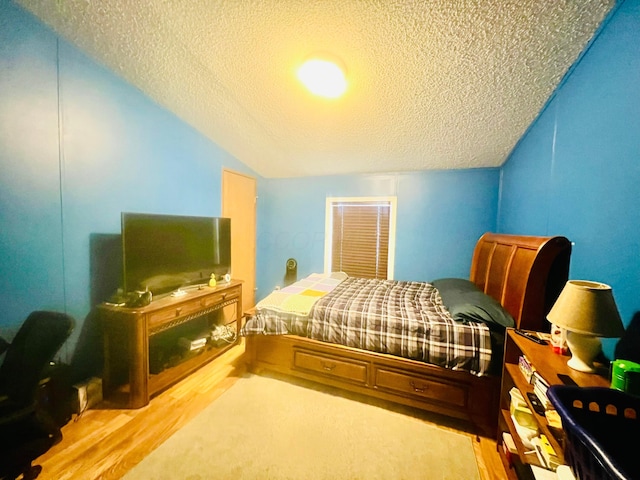 bedroom featuring hardwood / wood-style flooring, a textured ceiling, and vaulted ceiling