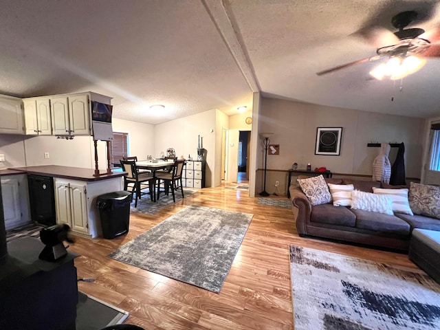 living room with vaulted ceiling, ceiling fan, a textured ceiling, and light wood-type flooring