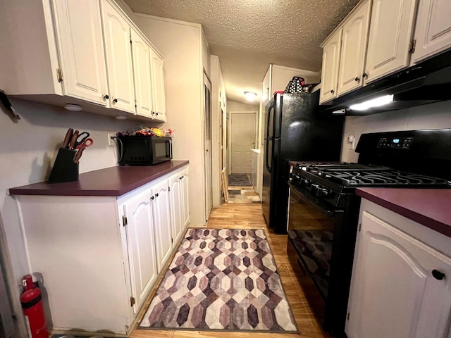 kitchen with white cabinetry, a textured ceiling, light wood-type flooring, and black appliances