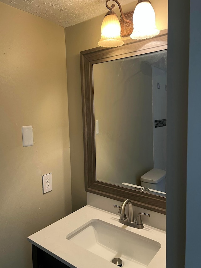 bathroom with toilet, a textured ceiling, and vanity