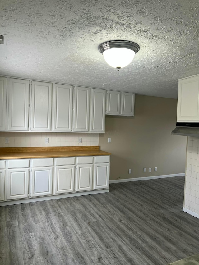 kitchen with dark wood-style floors, wooden counters, white cabinetry, and baseboards