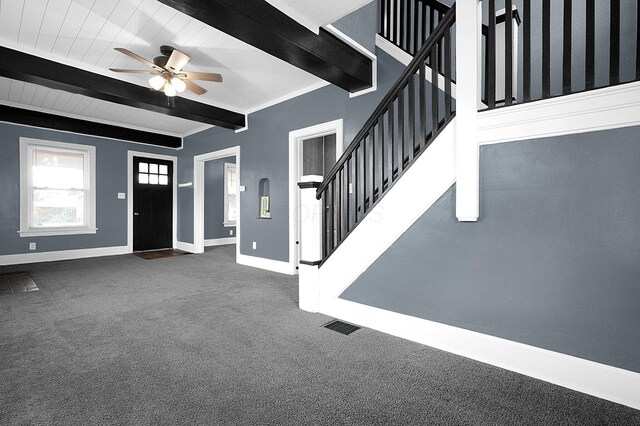 foyer featuring beamed ceiling, ceiling fan, and dark colored carpet