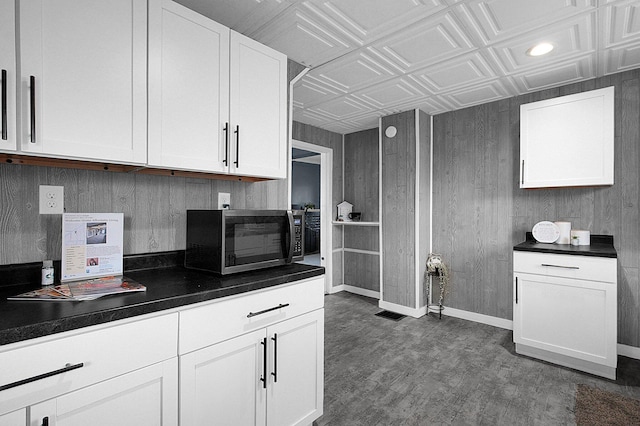 kitchen featuring white cabinetry and wooden walls