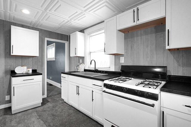 kitchen featuring wooden walls, white cabinetry, sink, dark hardwood / wood-style flooring, and gas range gas stove