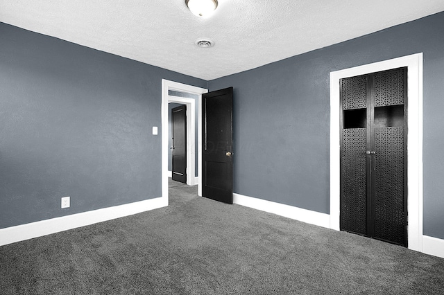 unfurnished bedroom featuring a textured ceiling and dark carpet