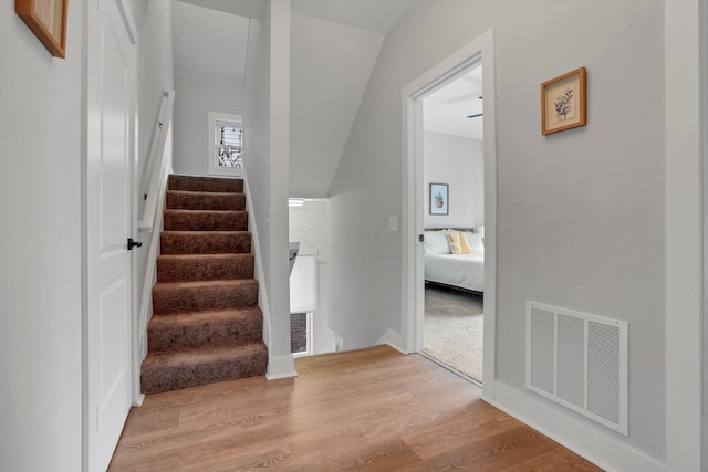 stairs with wood-type flooring and vaulted ceiling